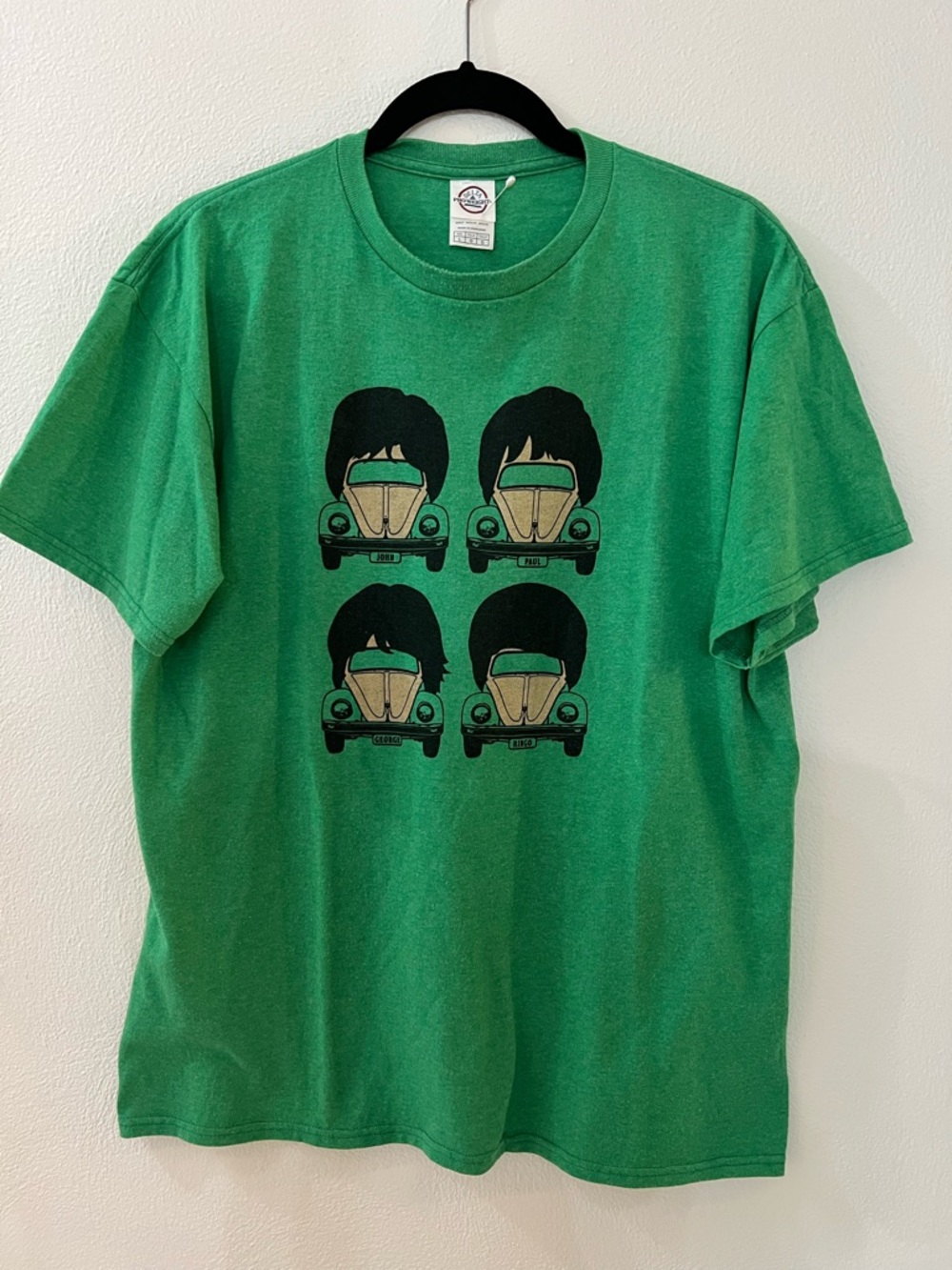 Vintage green Beatles VW cars that are topped with Beatles wigs haircuts designs